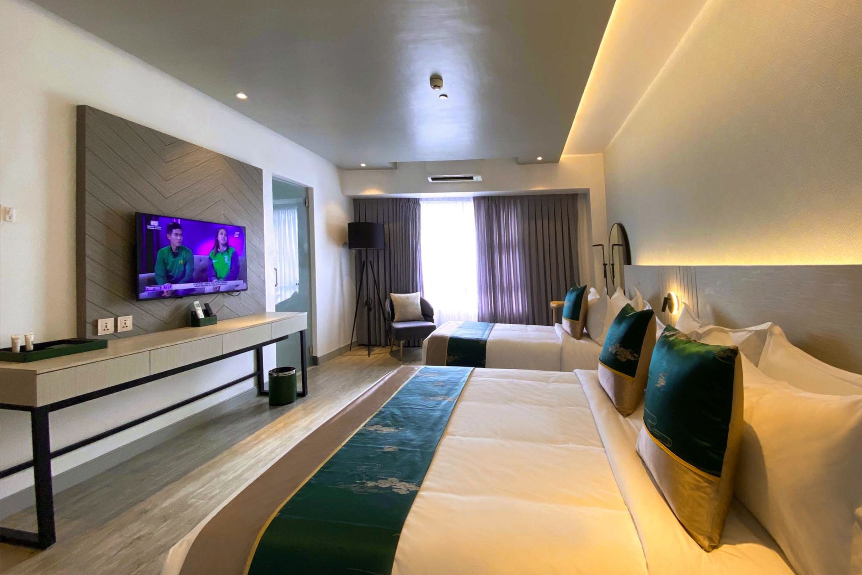 Habitación de hotel con televisión, escritorio, cama y ventana.