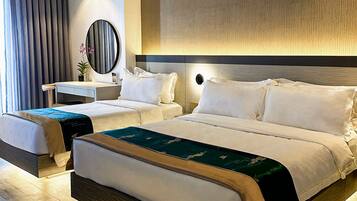 A hotel room with a large bed, a smaller bed, a desk, and a mirror.