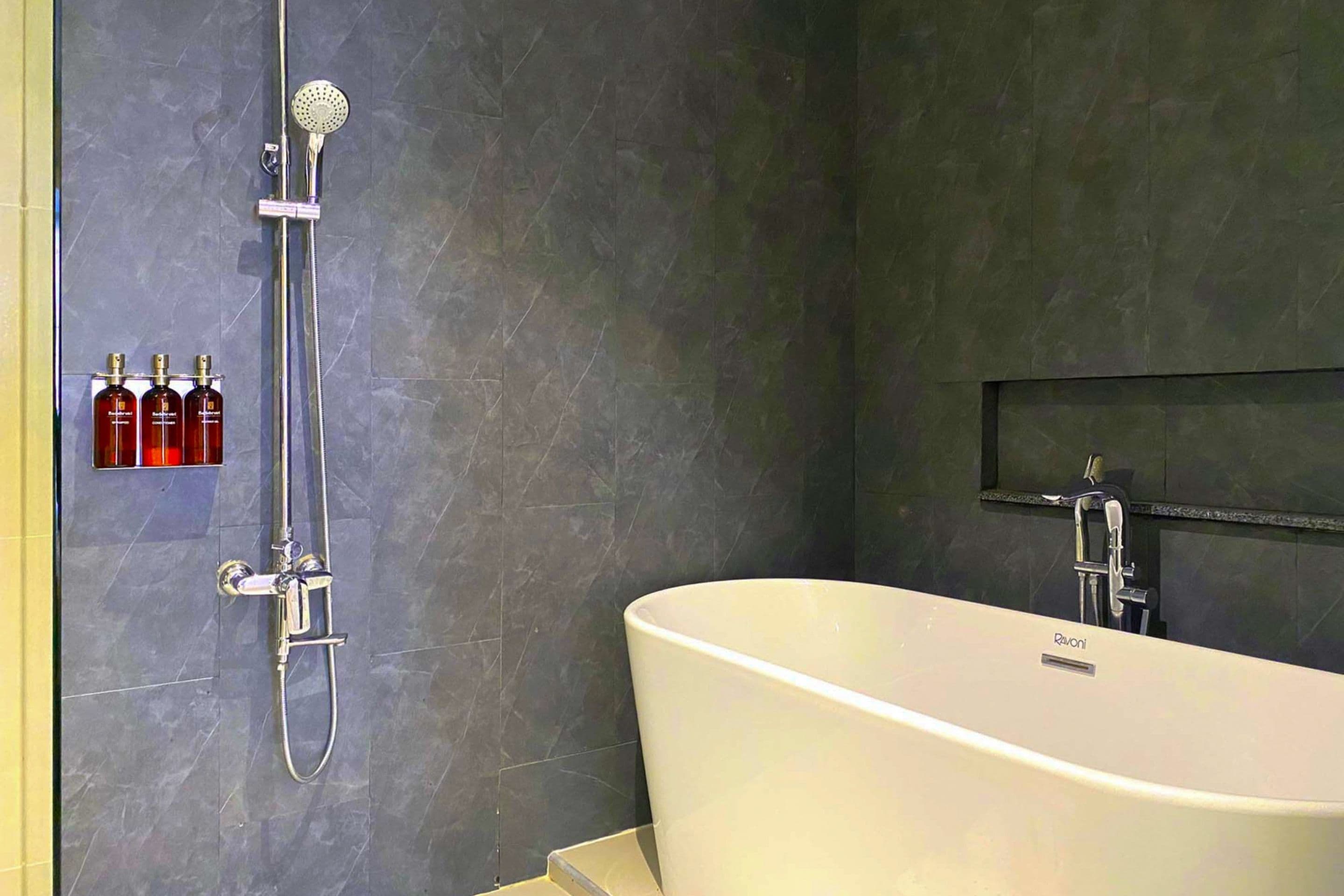 Un baño moderno con una bañera independiente, un cabezal de ducha manual y un grifo empotrado.