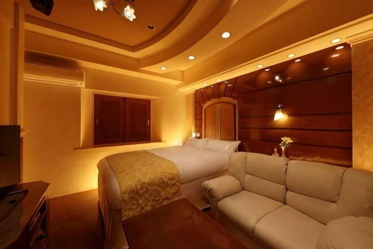 Een hotelkamer met een bed, een bank, een houten hoofdbord en een raam.