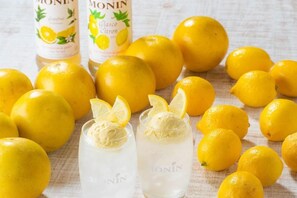 Bottles of lemon-flavored drink, lemons, and glasses with lemon slices.