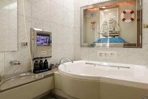 Un baño con una bañera grande, una pantalla digital y un adorno con forma de salvavidas.