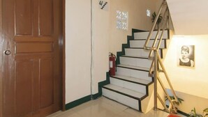 A wooden door, a staircase with a handrail, and a wall-mounted fire extinguisher. - RedDoorz @ Western Bicutan Transients Inn (Taguig)