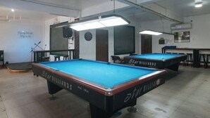 A billiards room with two Star Billiards pool tables, overhead lighting, and a dartboard on the wall. - RedDoorz @ Western Bicutan Transients Inn (Taguig)