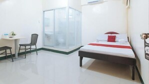 A hotel room with a bed, a desk, a chair, and a sliding glass door leading to a balcony. - RedDoorz @ Western Bicutan Transients Inn (Taguig)