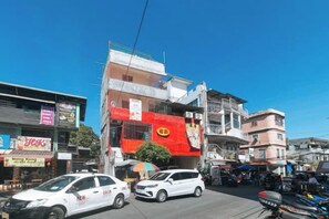A street scene with buildings, a white car, and a motorcycle. - RedDoorz @ Western Bicutan Transients Inn (Taguig)