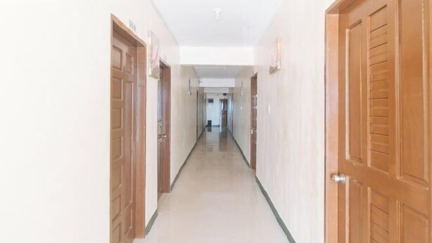 A long, narrow hallway with wooden doors on both sides, leading to a room at the end. - RedDoorz @ Western Bicutan Transients Inn (Taguig)