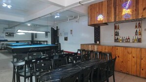 A bar area with wooden paneling and a neon sign, surrounded by pool tables and chairs. - RedDoorz @ Western Bicutan Transients Inn (Taguig)