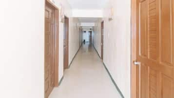 A corridor with wooden doors on both sides, leading to a room at the end.