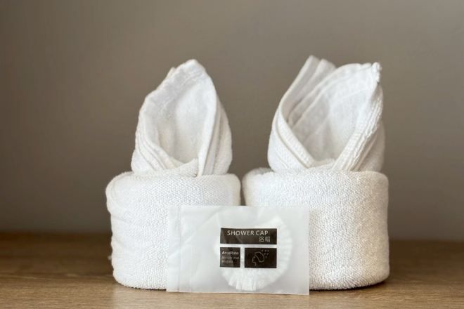 Two white towels with a label reading 'SHOWER CAP' and a small white package.