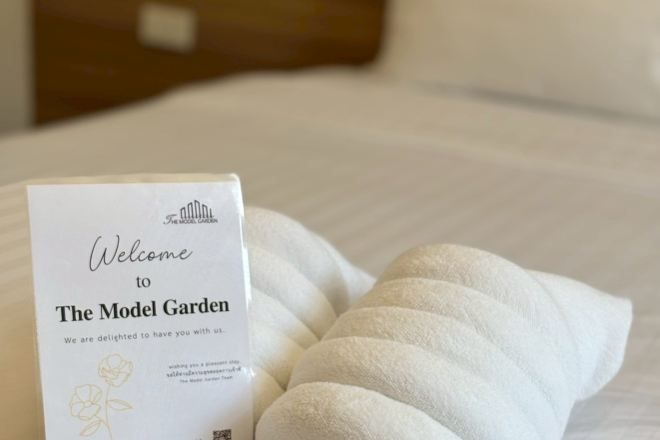 A welcome sign and a neatly folded towel on a bed.