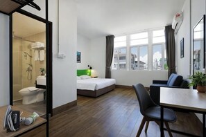 A hotel room with a bed, a desk, a chair, a shower area, and a view of the city. - Polaris Suite (Kota Kinabalu)