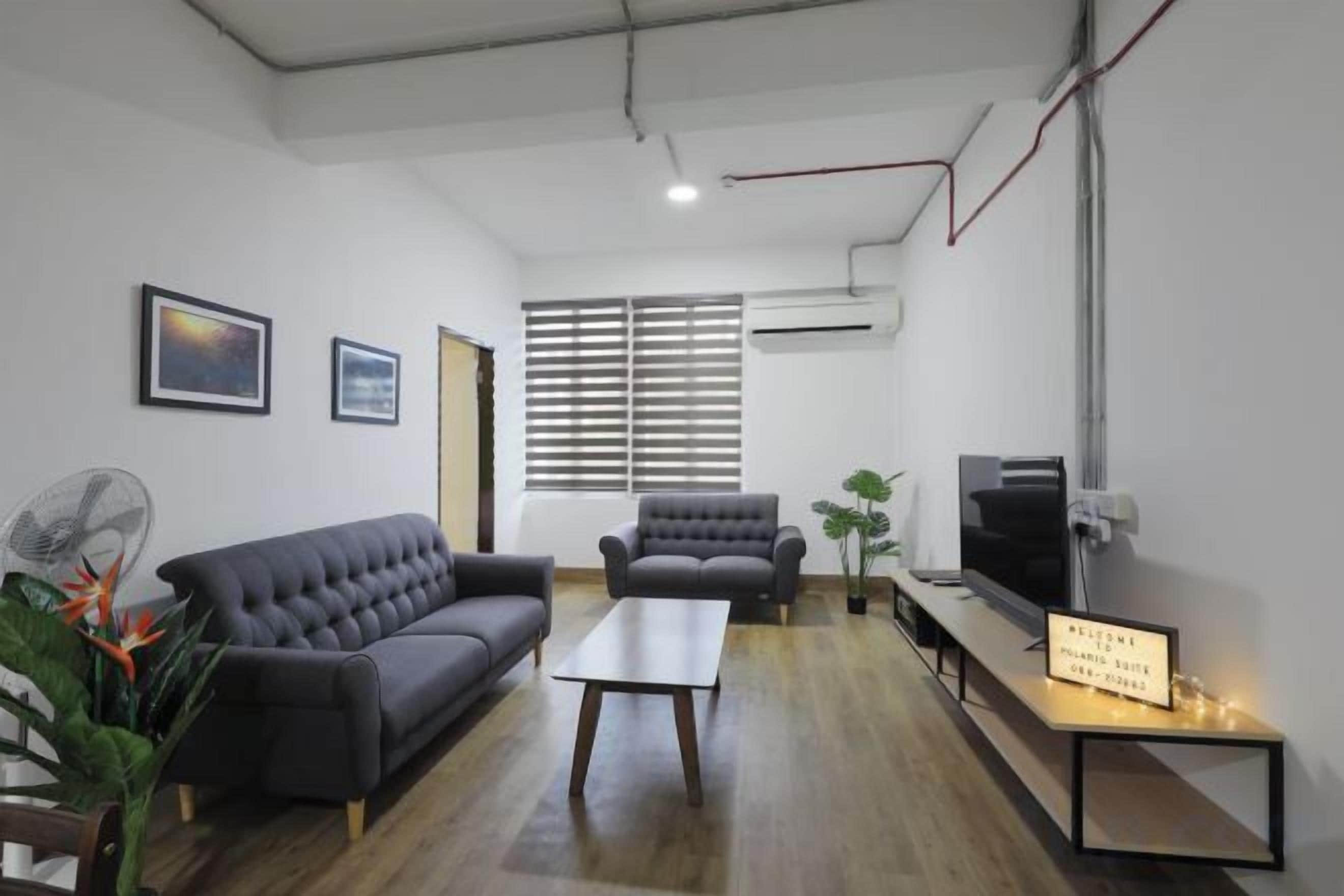 A modern living room with a sofa, armchair, and a flat-screen TV.