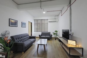 A modern living room with a sofa, armchair, and a flat-screen TV. - Polaris Suite (Kota Kinabalu)