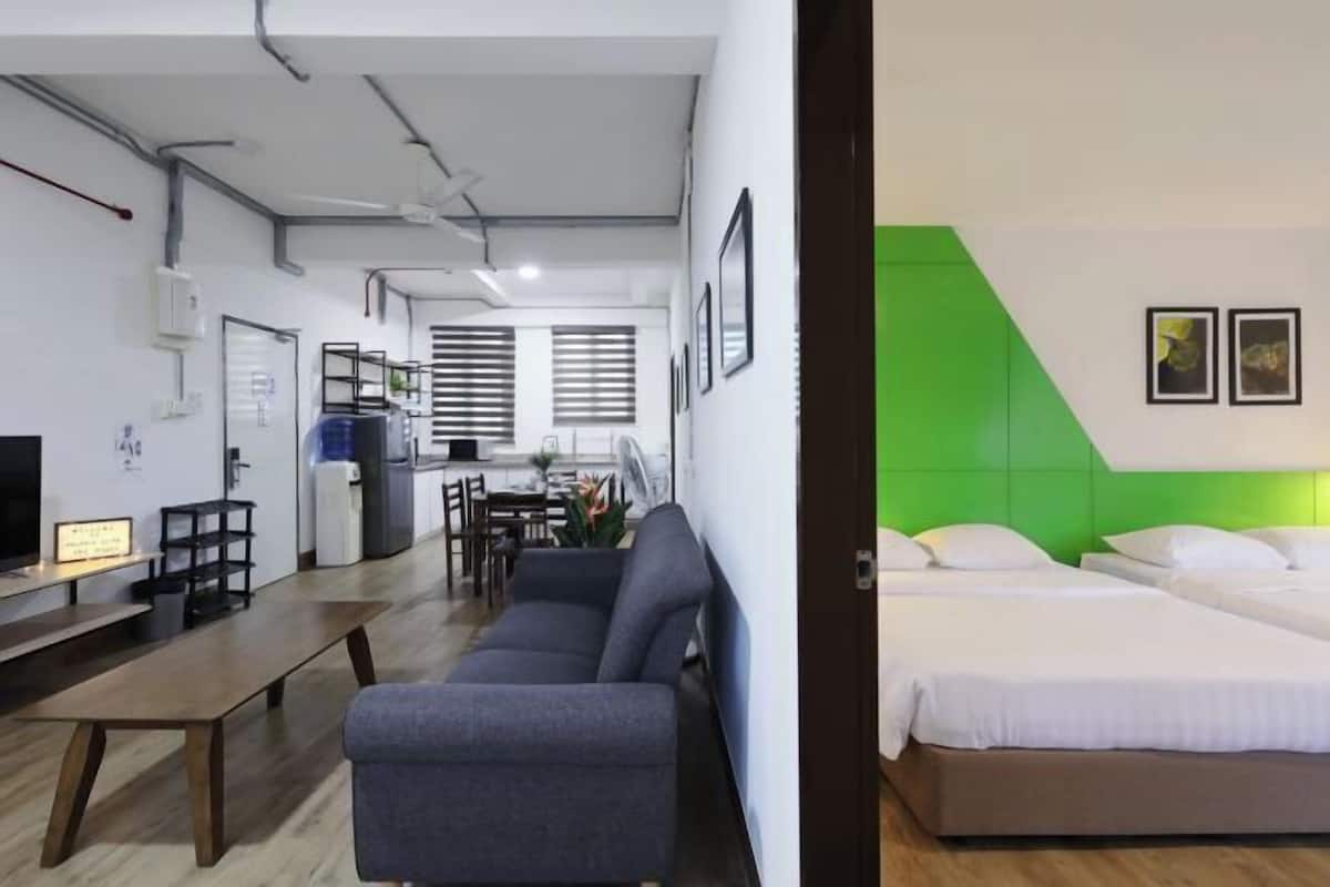 A modern hotel room with a sofa, a bed, and a dining area in the background.
