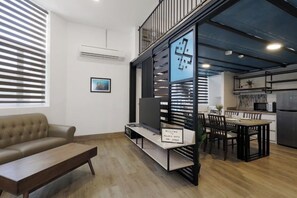 A modern living room with a sofa, a coffee table, a dining area with a table and chairs, and a kitchen in the background. - Polaris Suite (Kota Kinabalu)