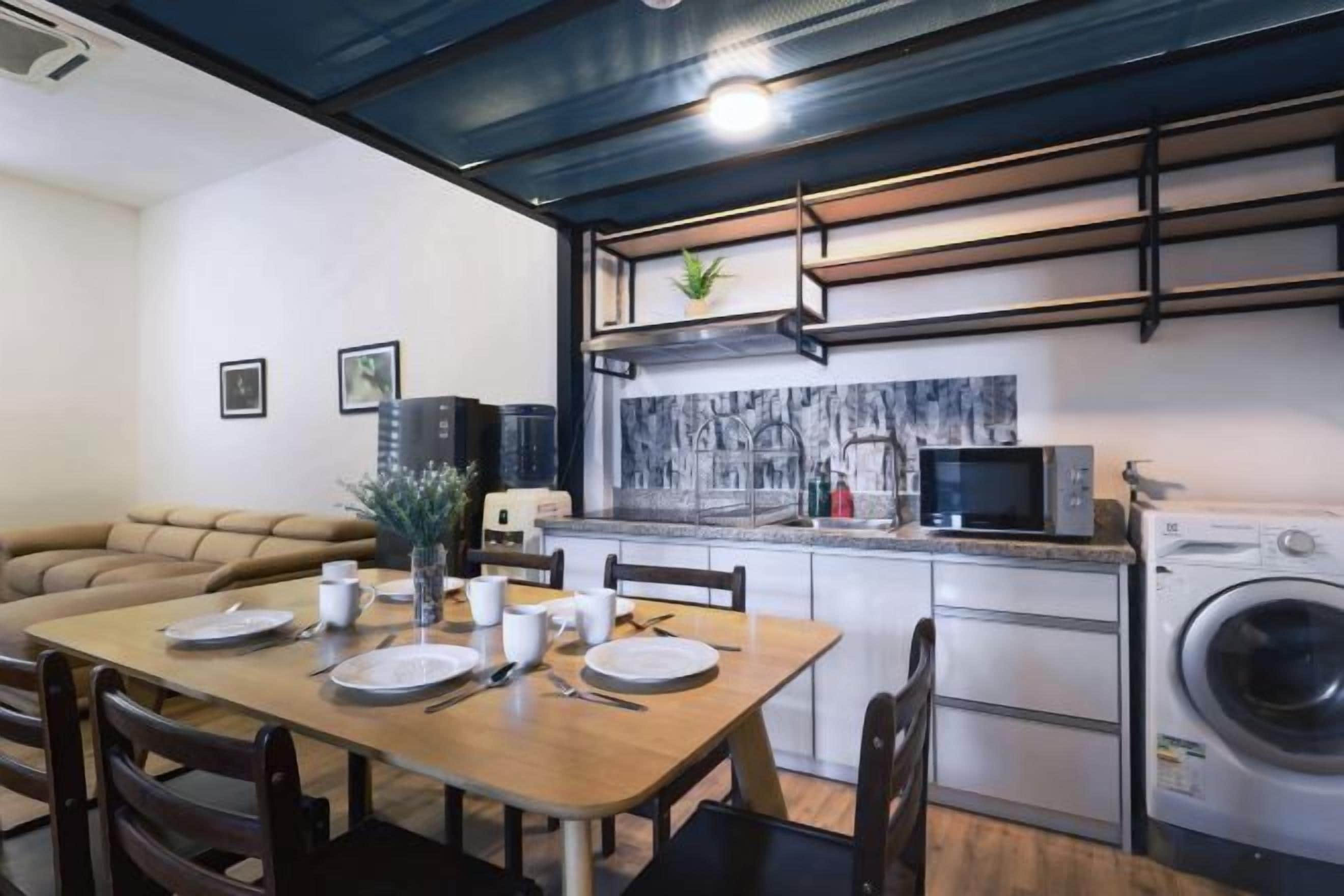 A compact living space with a dining area, kitchenette, and a washing machine.