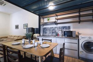 A compact living space with a dining area, kitchenette, and a washing machine. - Polaris Suite (Kota Kinabalu)