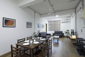 Un comedor con mesa y sillas de madera, un sofá y una mesa baja.