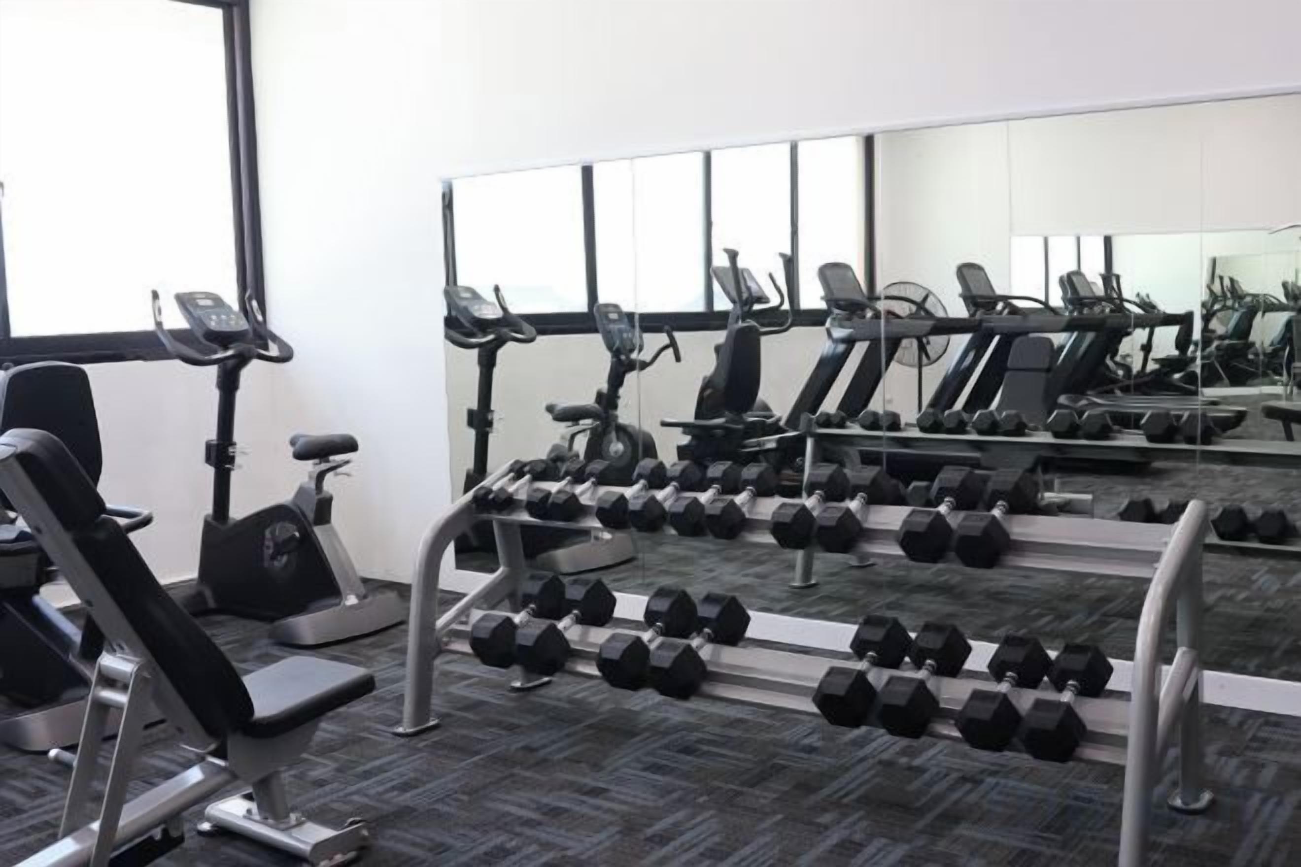 Une salle de sport équipée de matériel d’exercice, notamment des tapis de course, des haltères et des appareils de musculation.
