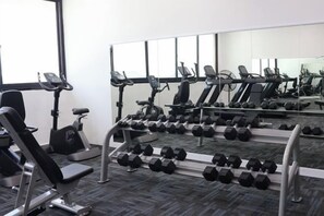Ett gym med träningsutrustning, inklusive löpband, hantlar och styrketräningsmaskiner.