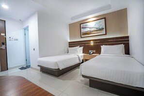 A hotel room with two beds, a wooden floor, a painting on the wall, and a nightstand with a phone. - Alimoer Hotel Kubu Raya (Raya River)