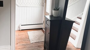 A room with a wooden floor, a white radiator, a dark wooden desk, a white rug, and a patterned wallpaper. - Cozy 3 bedroom home with perfect location in Saint John (Saint John)