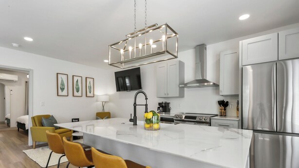 A modern kitchen with a central island, white cabinetry, stainless steel appliances, and a pendant light fixture.
