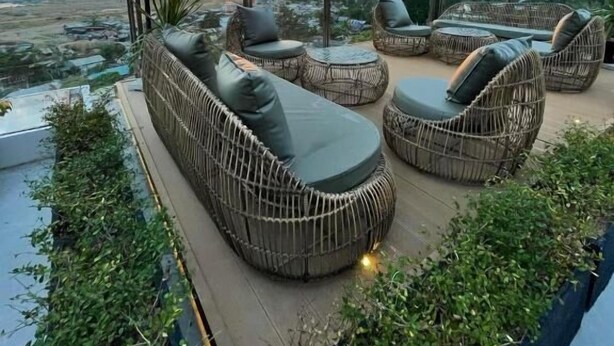 A rooftop terrace with wicker furniture, a large umbrella, and a sunset view. - Coron 180 Hotel (Coron)