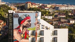 A hotel with a mural of a person, balconies, and a view of the sea. - Coron 180 Hotel (Coron)