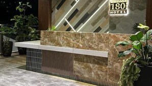A hotel reception area with a modern design, including a reception desk, a sign for 'CORON 180 HOTEL,' and potted plants. - Coron 180 Hotel (Coron)