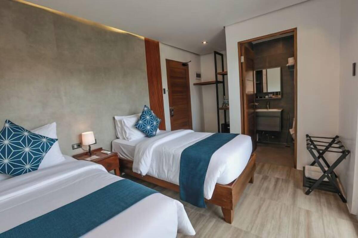 A hotel room with two beds, a bathroom, and a small seating area.