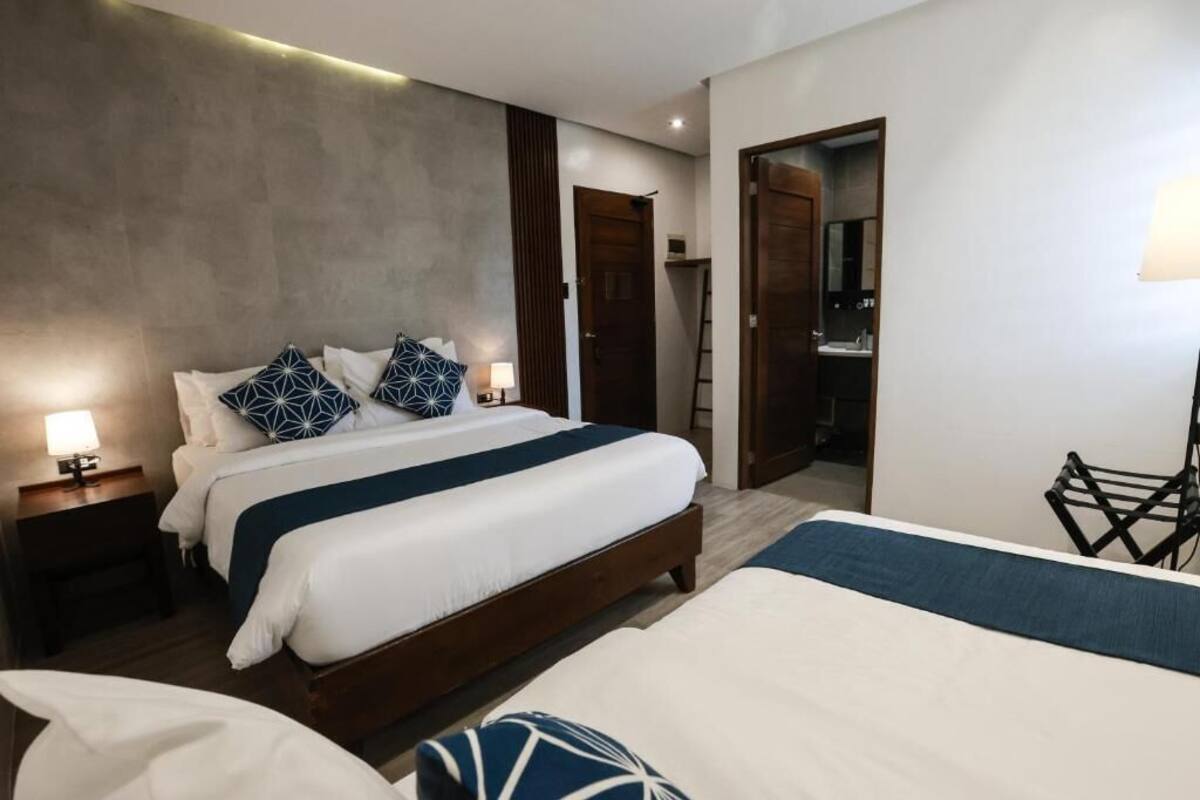 A hotel room with a large bed, bedside tables, a desk, and a bathroom visible through an open door.
