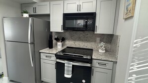 A modern kitchen with stainless steel appliances, granite countertops, and white cabinetry. - Charming  Two bedroom house near Beaches and Tampa Bay attractions. (Oldsmar)