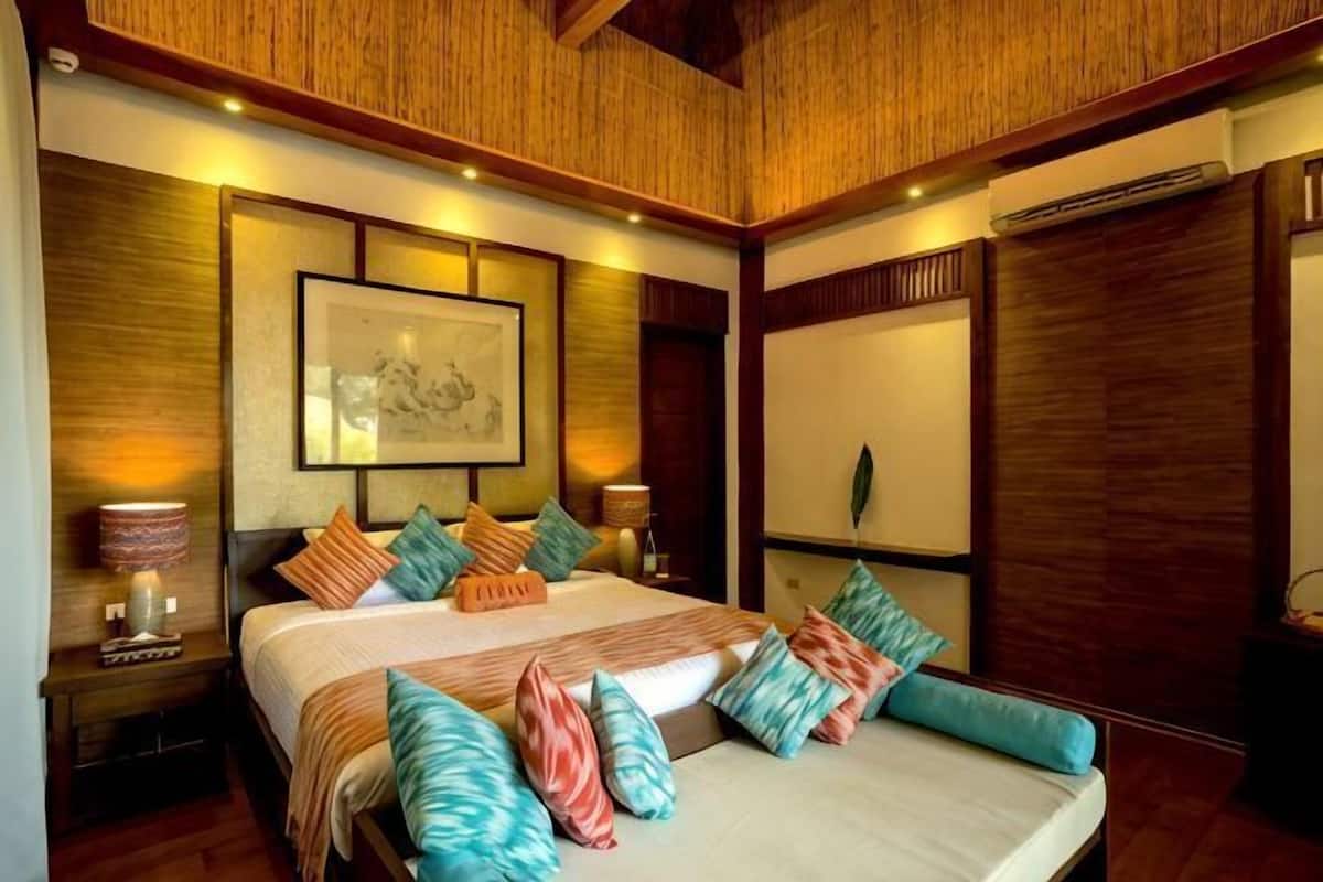 A bedroom with a large bed, wooden headboard, and a framed picture on the wall.