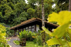 A thatched-roof building surrounded by lush greenery. - Lihim Resorts (El Nido)