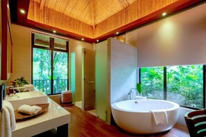 A modern bathroom with a large bathtub, a vanity with a sink, and a shower area. - Lihim Resorts (El Nido)
