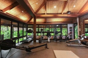 A gym with exercise equipment, large windows, and a wooden ceiling. - Lihim Resorts (El Nido)