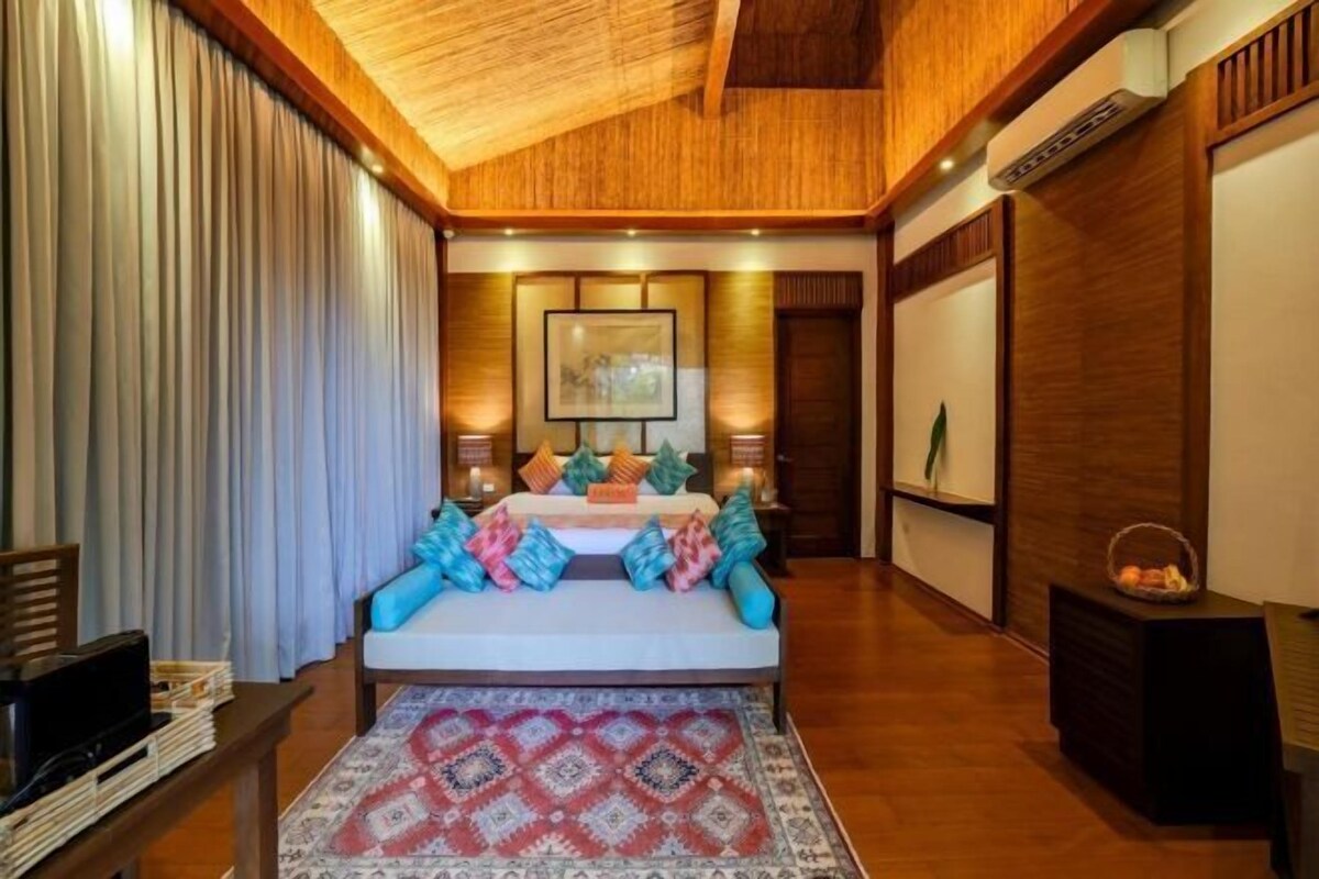 A spacious bedroom with a large bed, a wooden ceiling, and a view of the outdoors.