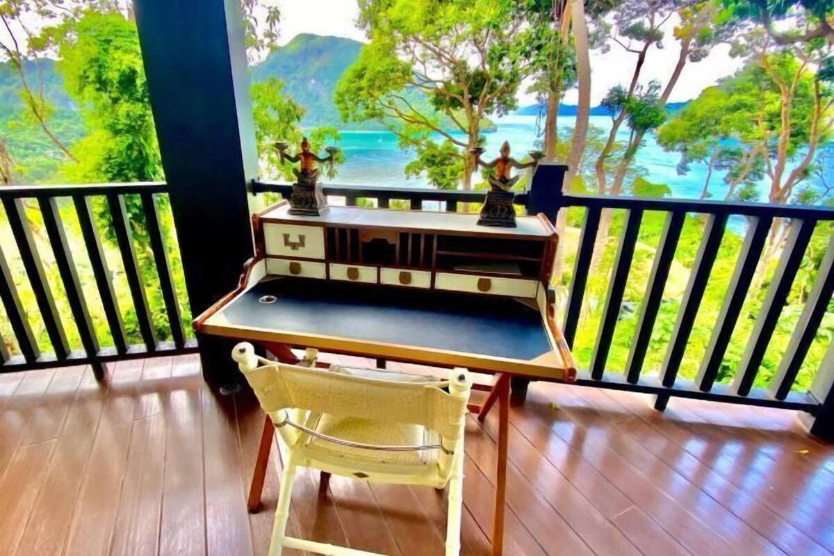 A wooden deck with a table and chair, overlooking a lush green landscape and a body of water.