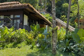 A thatched-roof building with a wooden deck, surrounded by lush tropical vegetation. - Lihim Resorts (El Nido)