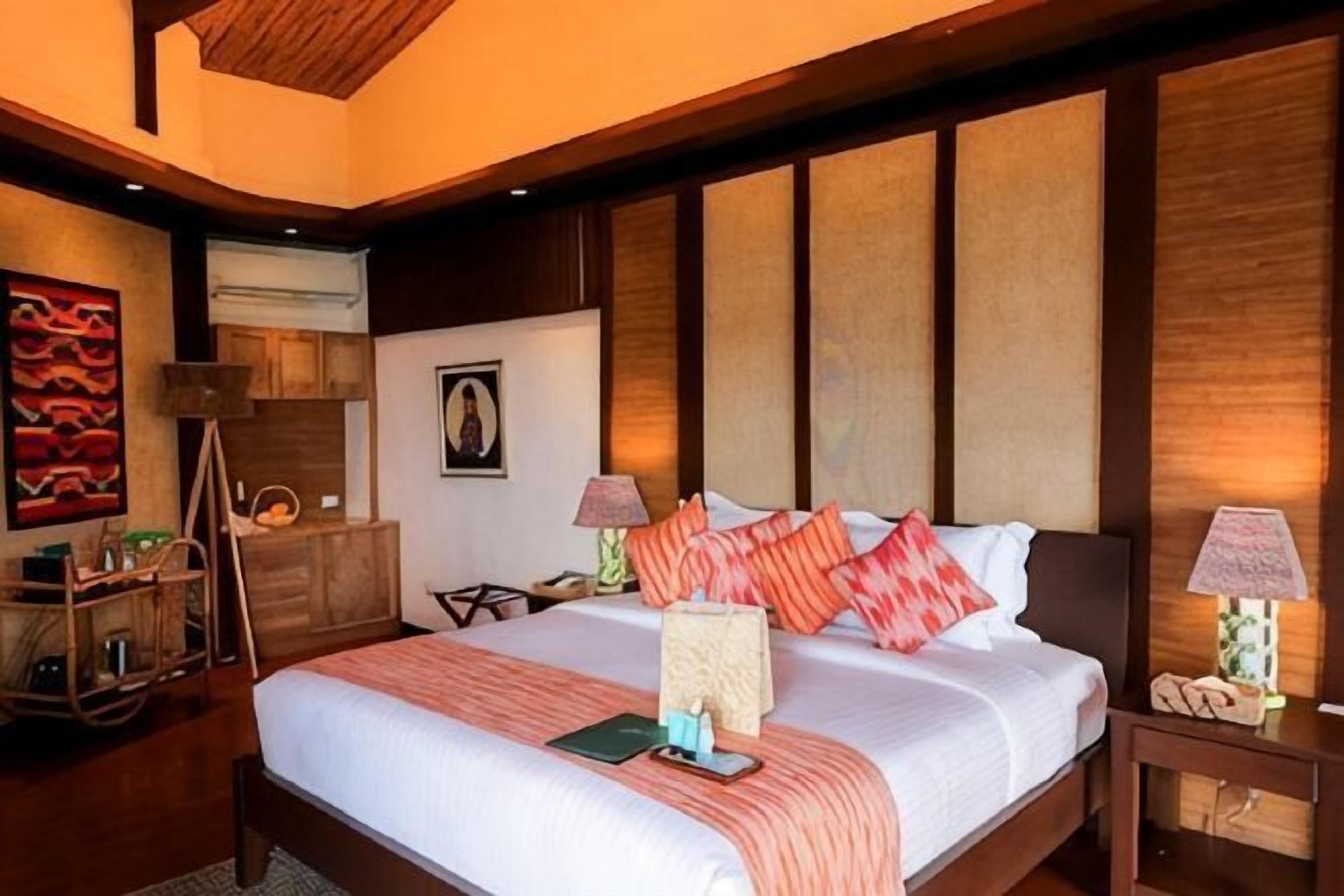 A bedroom with a large bed, wooden headboard, bedside tables, and a nightstand.