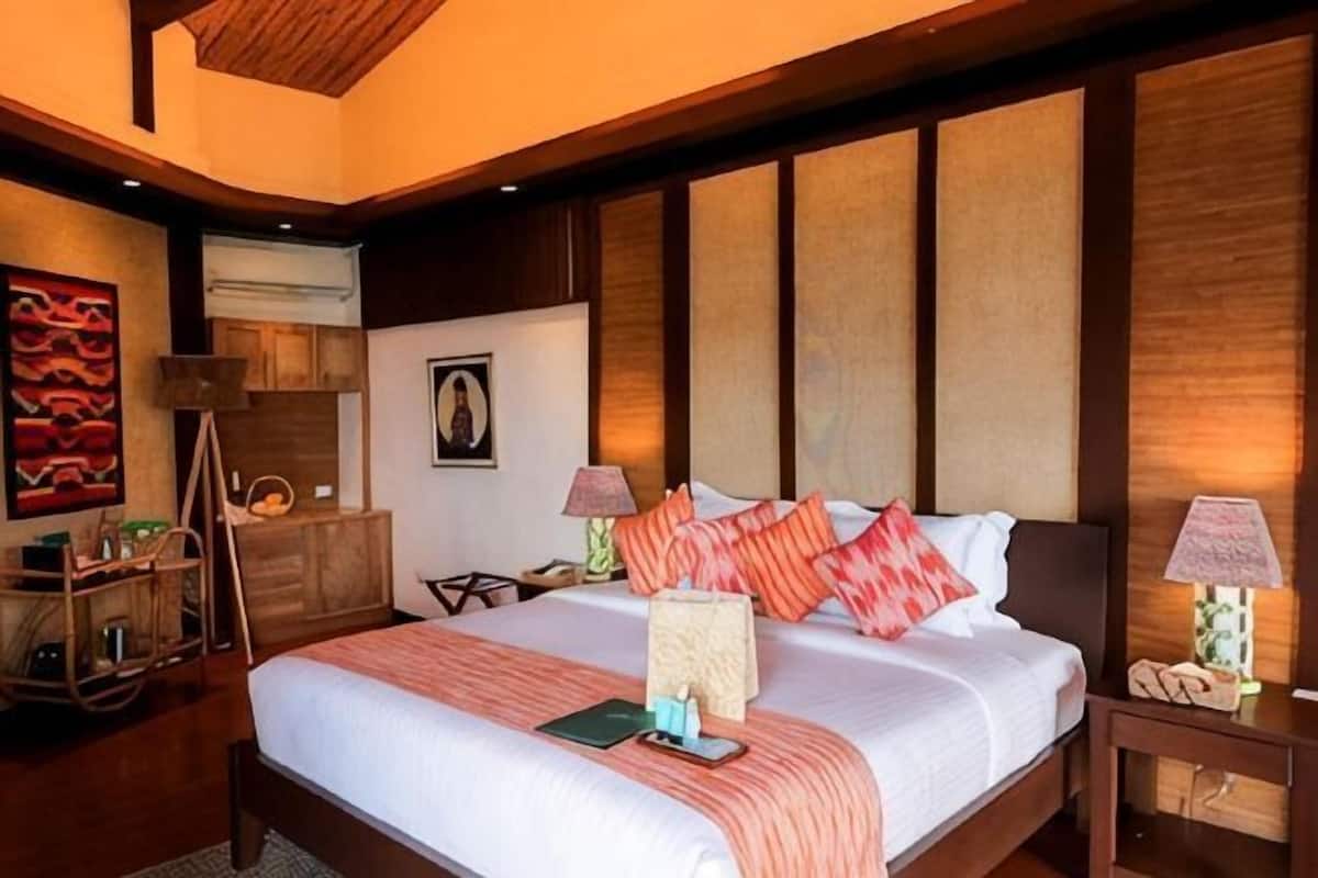 A bedroom with a large bed, wooden headboard, bedside tables, and a nightstand.