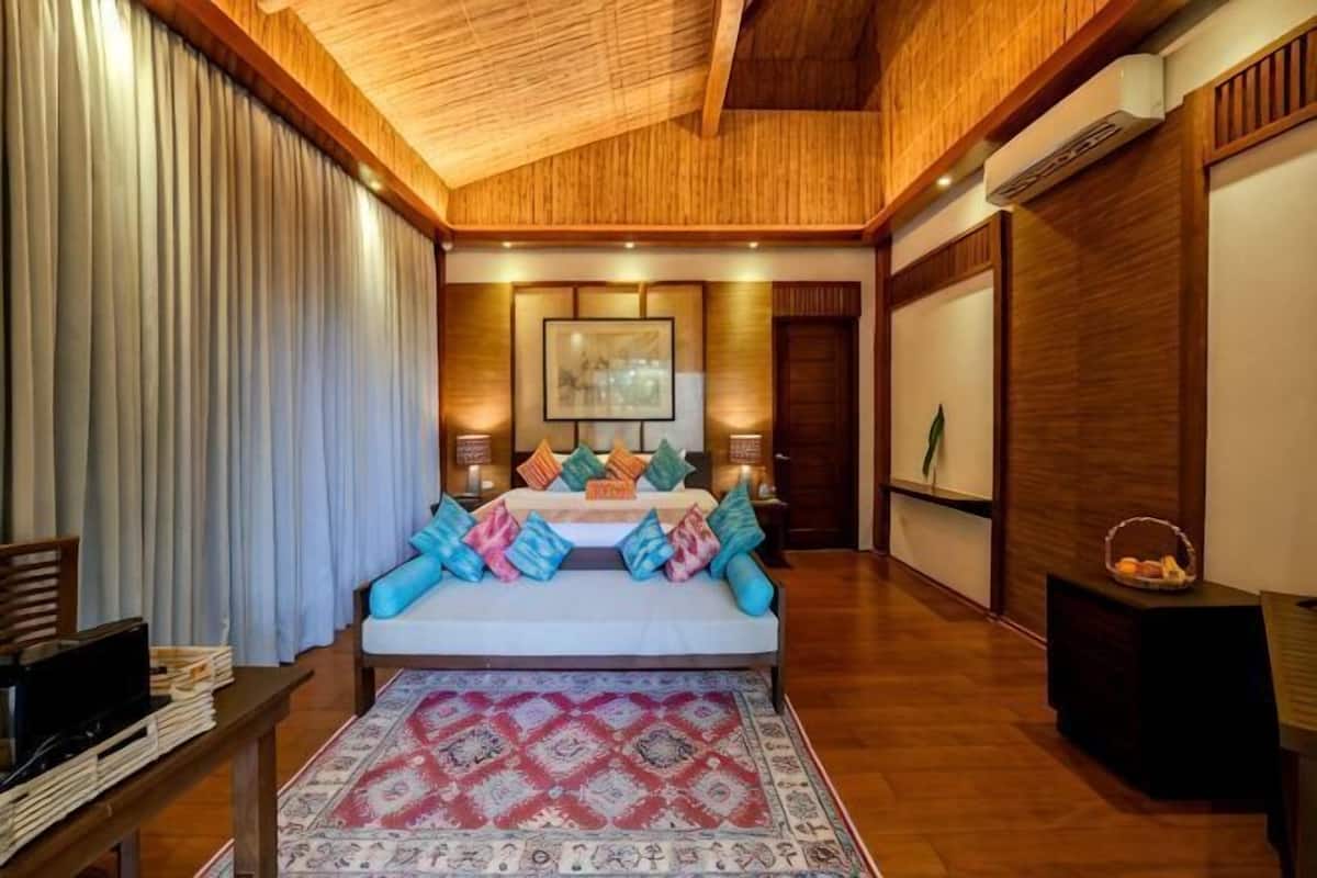 A bedroom with a bed, pillows, a rug, a desk, and a chair.