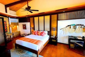 A bedroom with a bed, bedside tables, a desk, and a ceiling fan. - Lihim Resorts (El Nido)