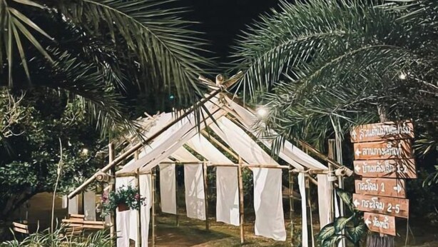 A rustic wooden structure with a thatched roof, surrounded by lush greenery. - Pitifarmily Cafe & Camping (Kantharalak)