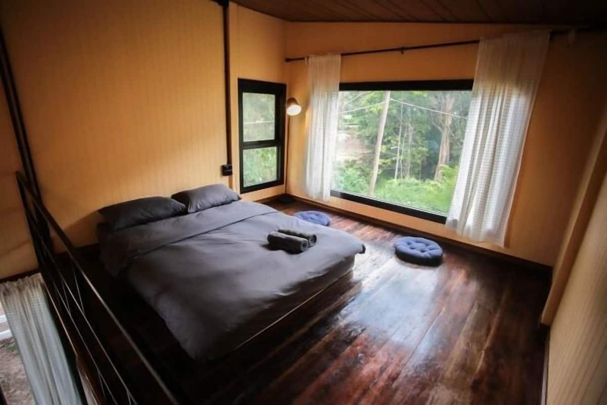Un dormitorio con cama, ventana y vista a zonas verdes.