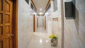 Un couloir doté d’un sol en marbre, de portes en bois et d’une boîte électrique fixée au mur.