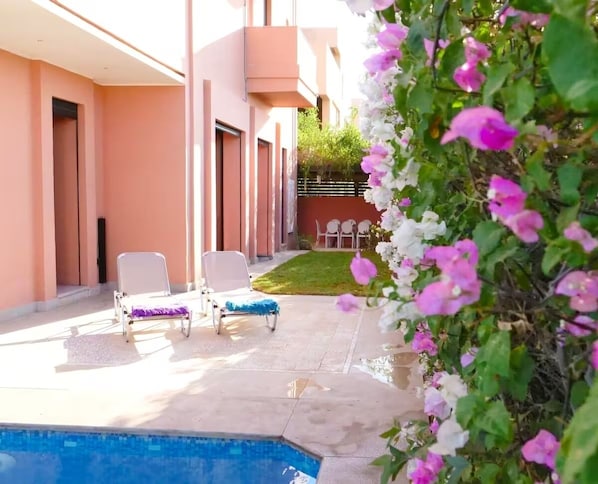 A poolside area with lounge chairs, a small pool, and a garden with pink flowers. - Stunning villa with a private pool and a playhouse for children (MX62+8Q6 (ref GPS))