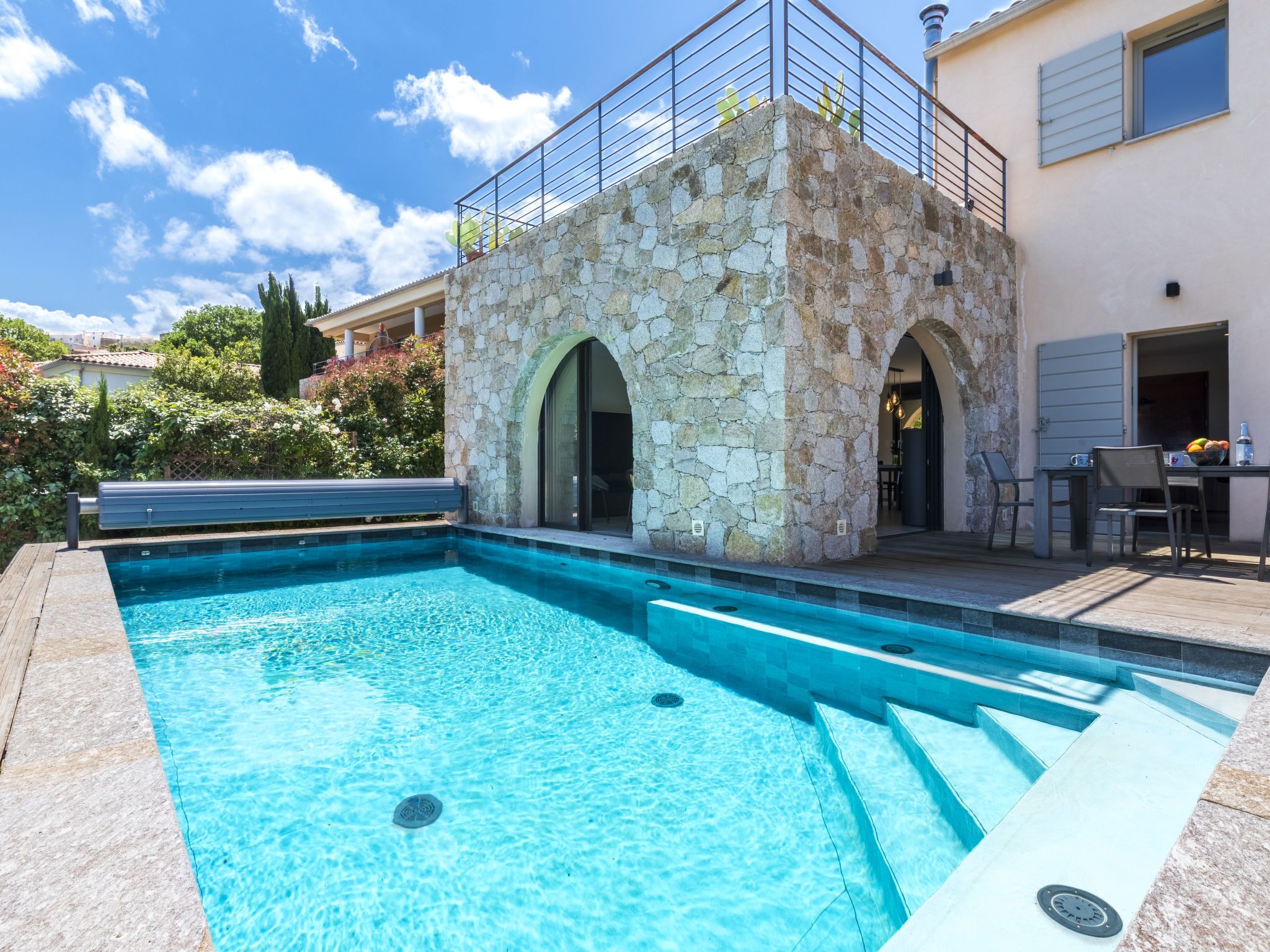 A swimming pool with stone walls and a covered patio area.